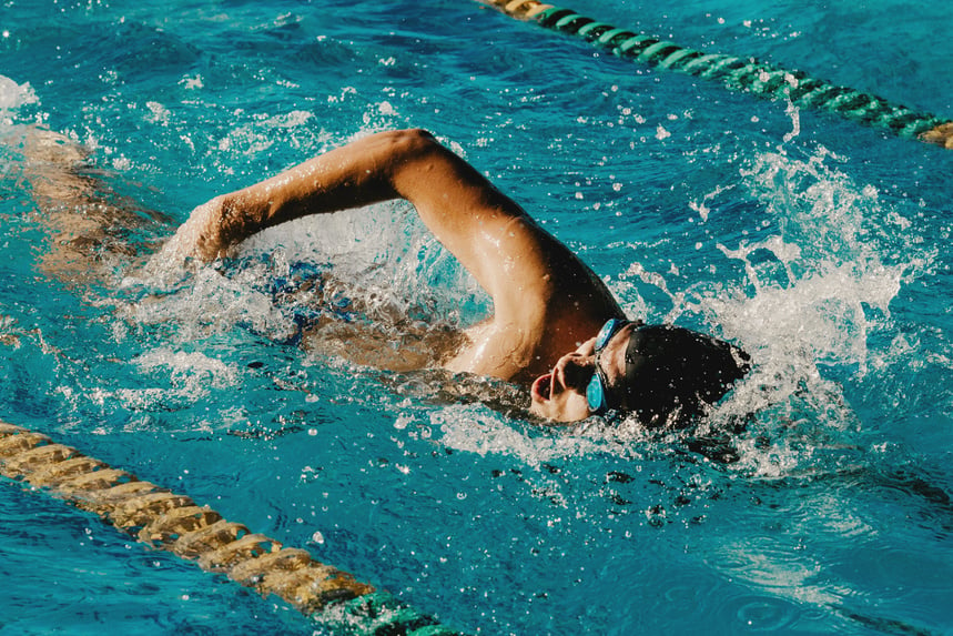 Professional swimmer floating in swimming pool with clean water